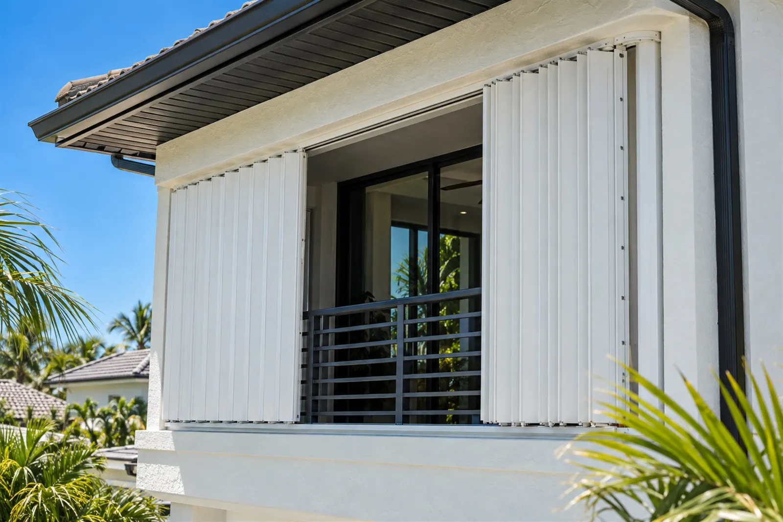 White accordion shutters folded open beside a second-floor balcony