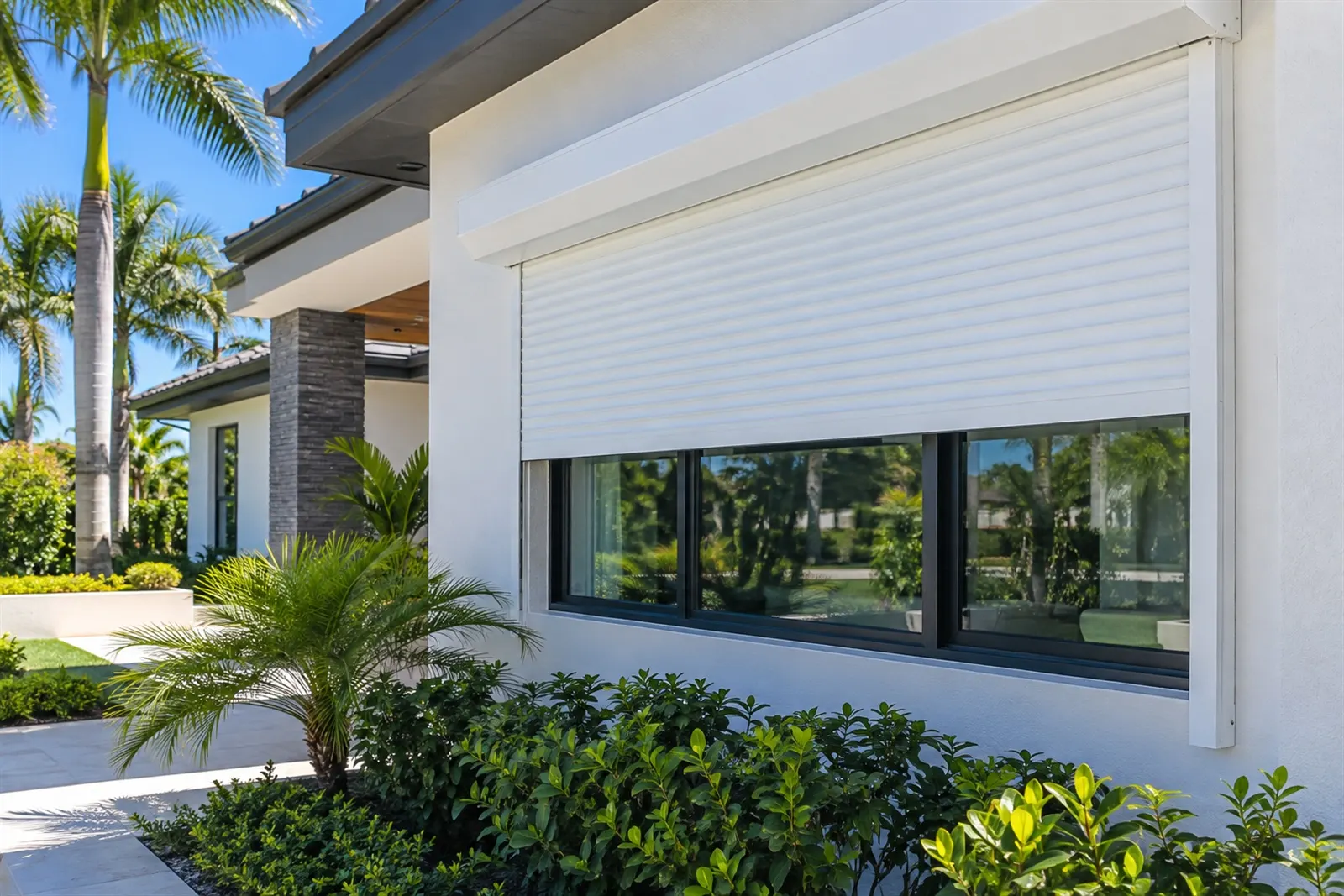 A white roll-down shutter partly lowered over a wide window